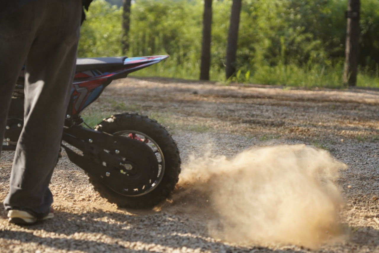 An Ogemaw 40 kids' dirt bike spins its wheels, kicking up dirt.