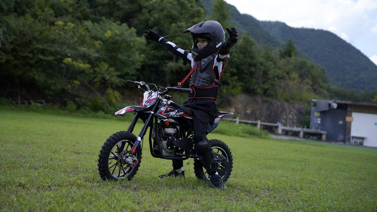 Kid in full riding gear celebrating next to an FRP FX40 40cc kids dirt bike on a grass field