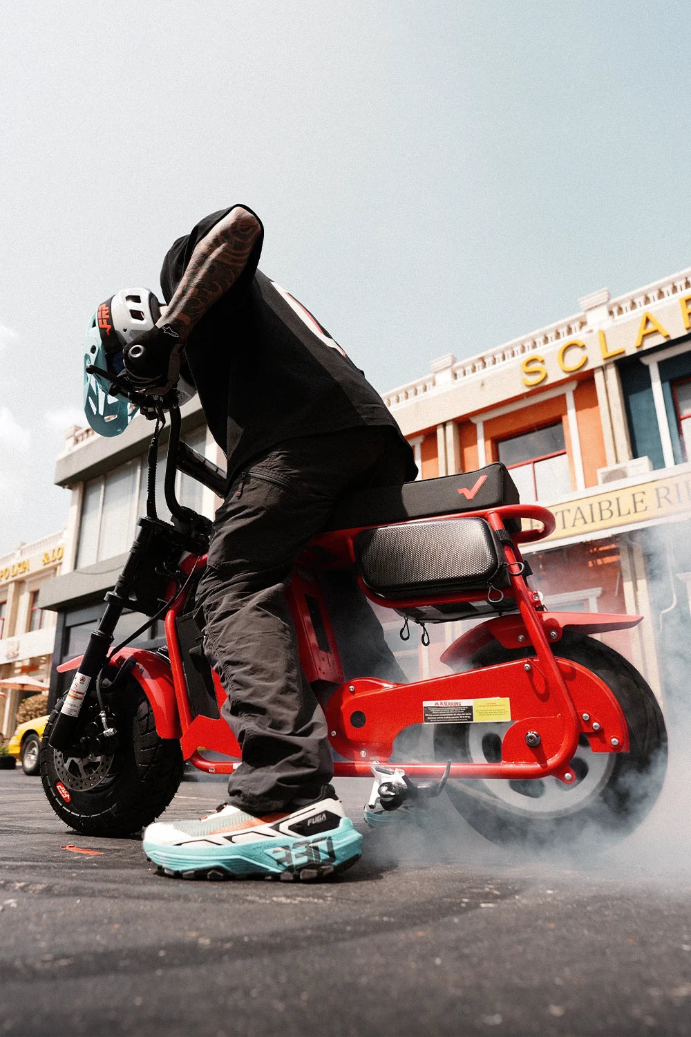 Rider doing a burnout on a red FRP M3 electric mini bike on a city street