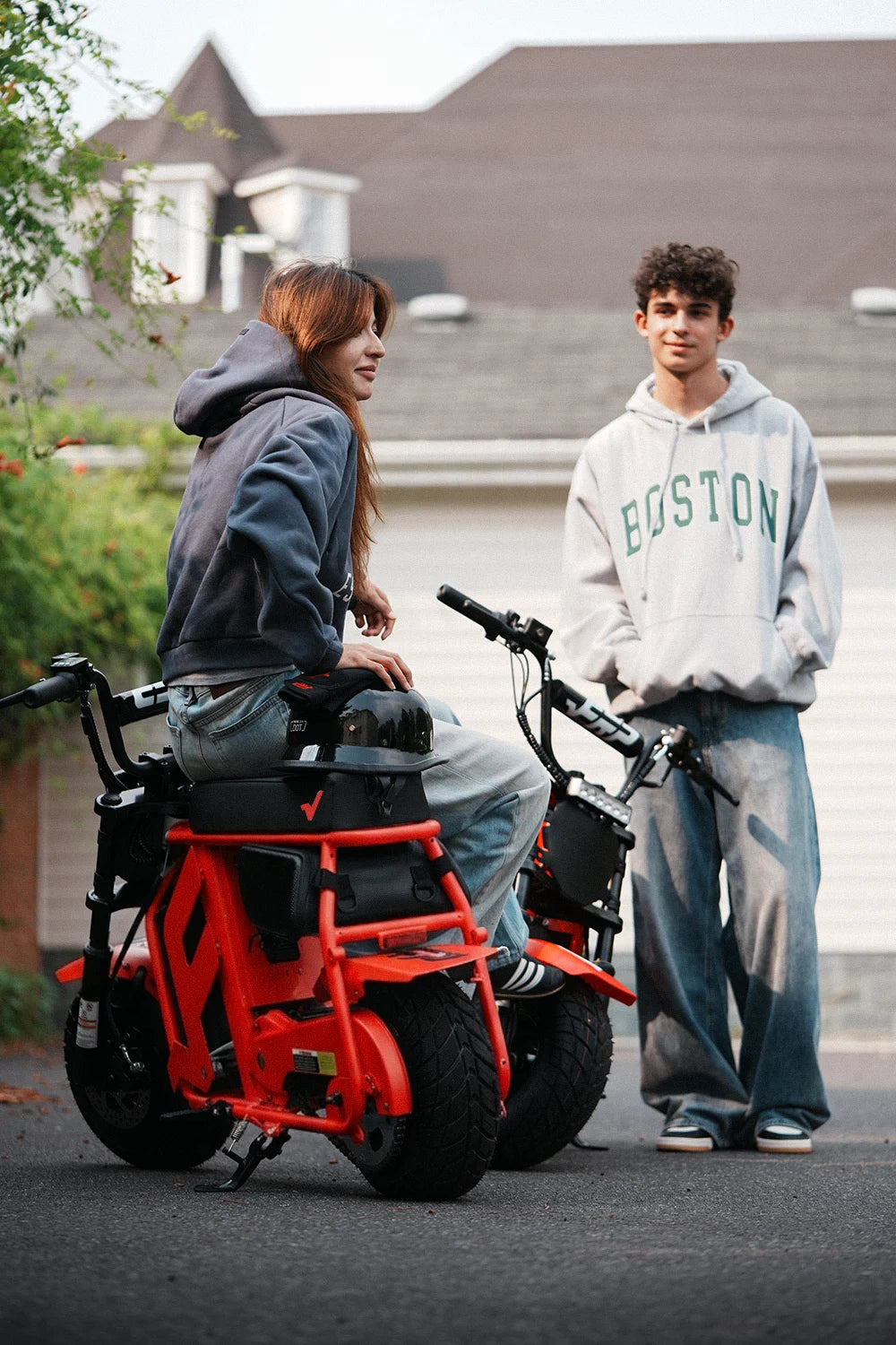 Two friends hanging out with orange FRP M3 electric mini bikes