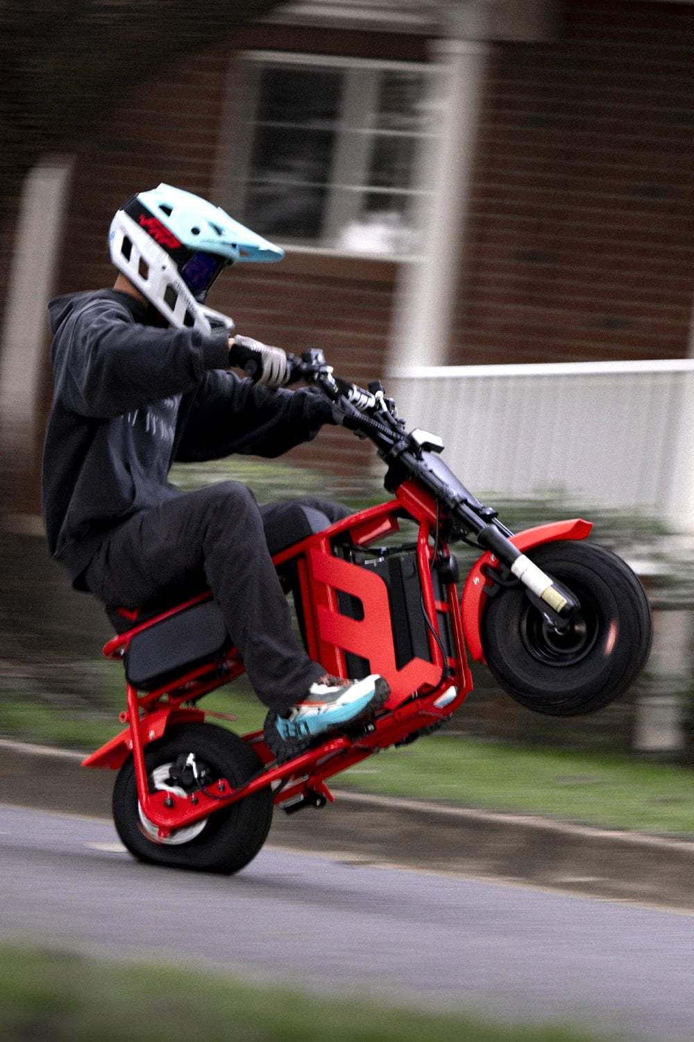 Rider popping a wheelie on a red FRP M3 electric mini bike