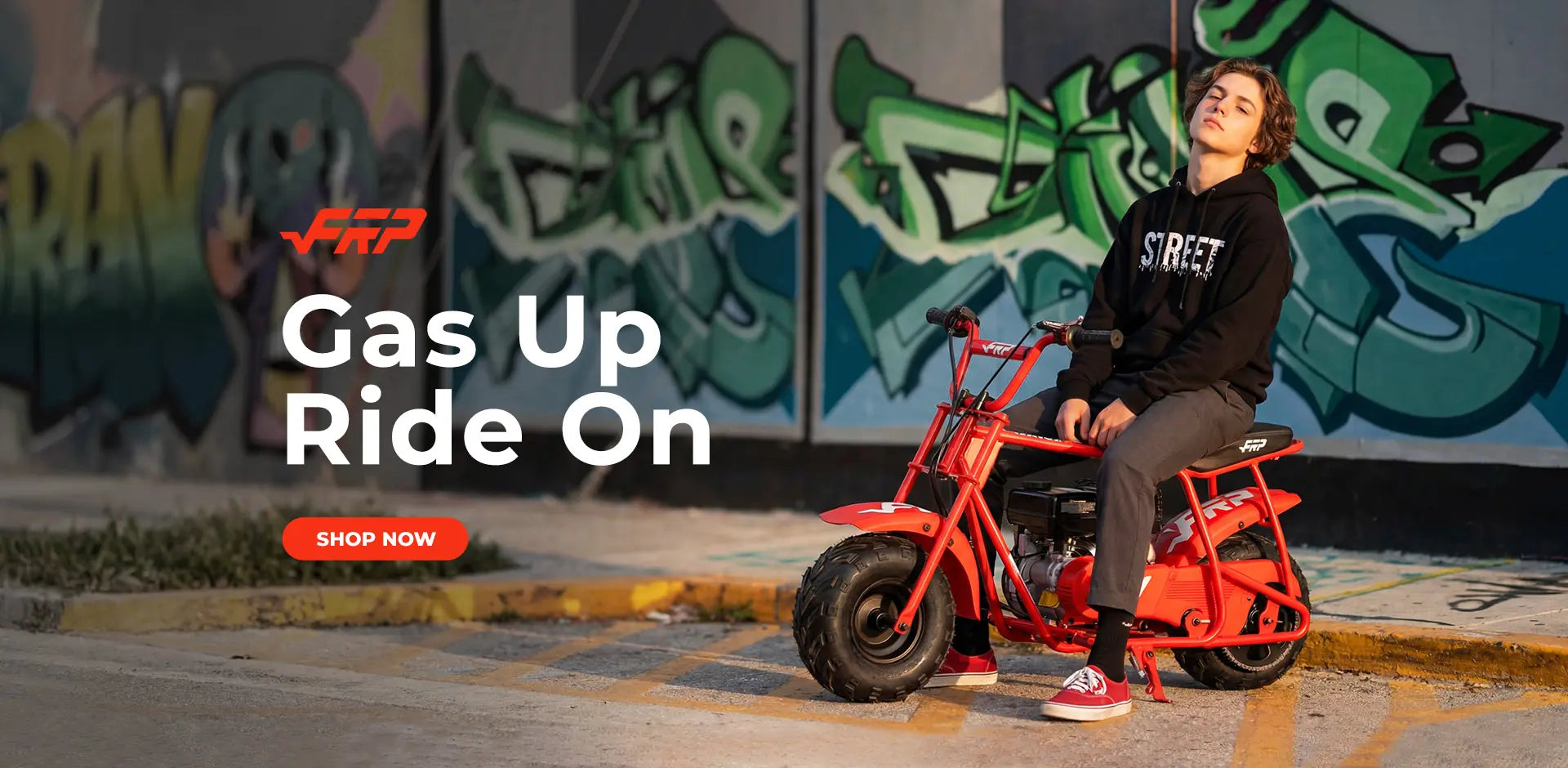 youth sitting on a red mini bike with graffiti in the background